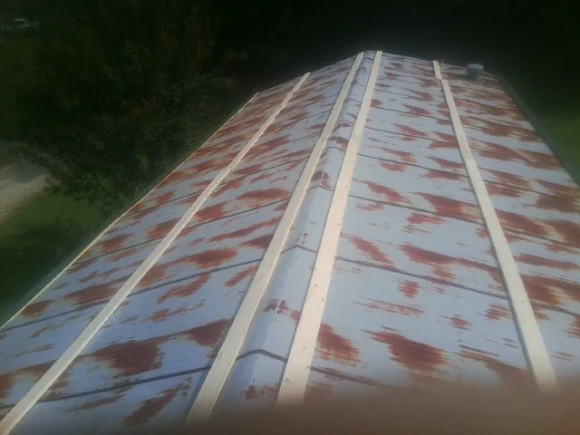 Rusted metal roof panels with new wood purlins before replacement — Storm Damage Roof Repair in Sacred Heart by Roofing Brothers