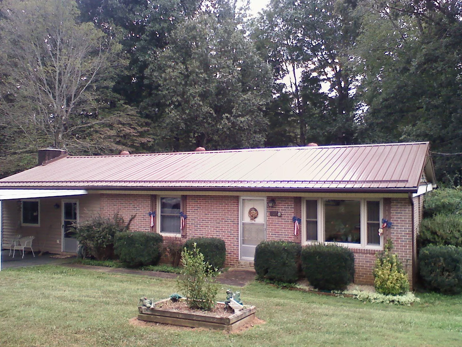 Bronze metal roof on a brick ranch home with a carport in Sacred Heart
