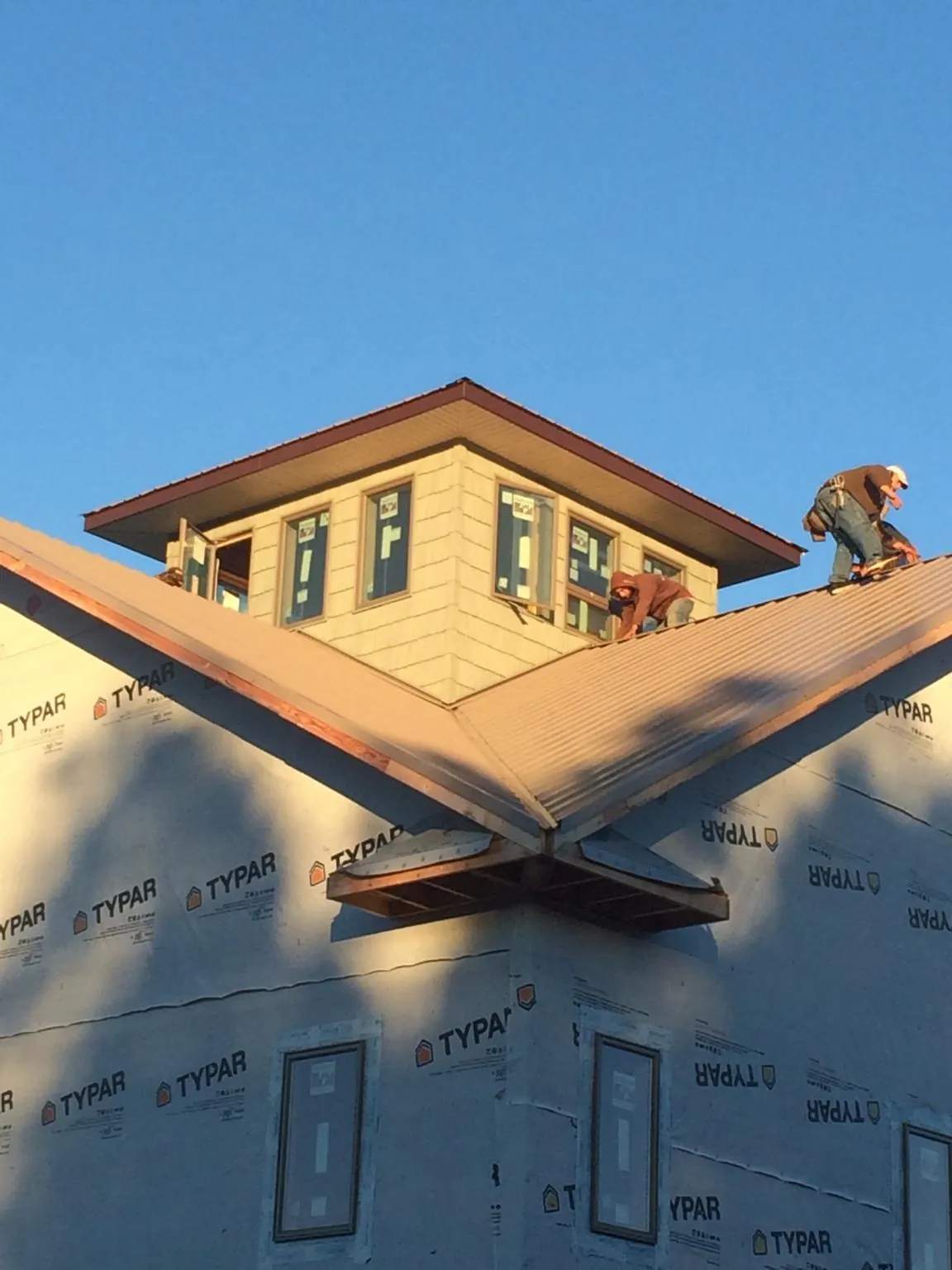 Roofers working around a rooftop cupola on a new metal roof at sunset — Roof Waterproofing in Sacred Heart by Roofing Brothers